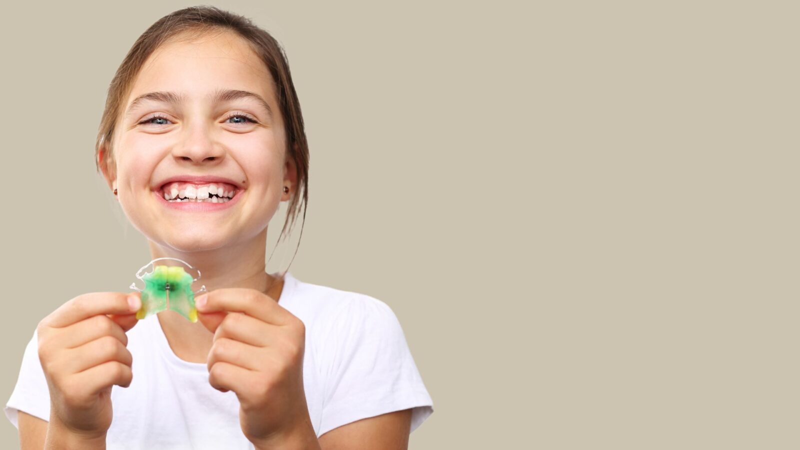 Laughing girl holding a removable brace with a green plastic plate
