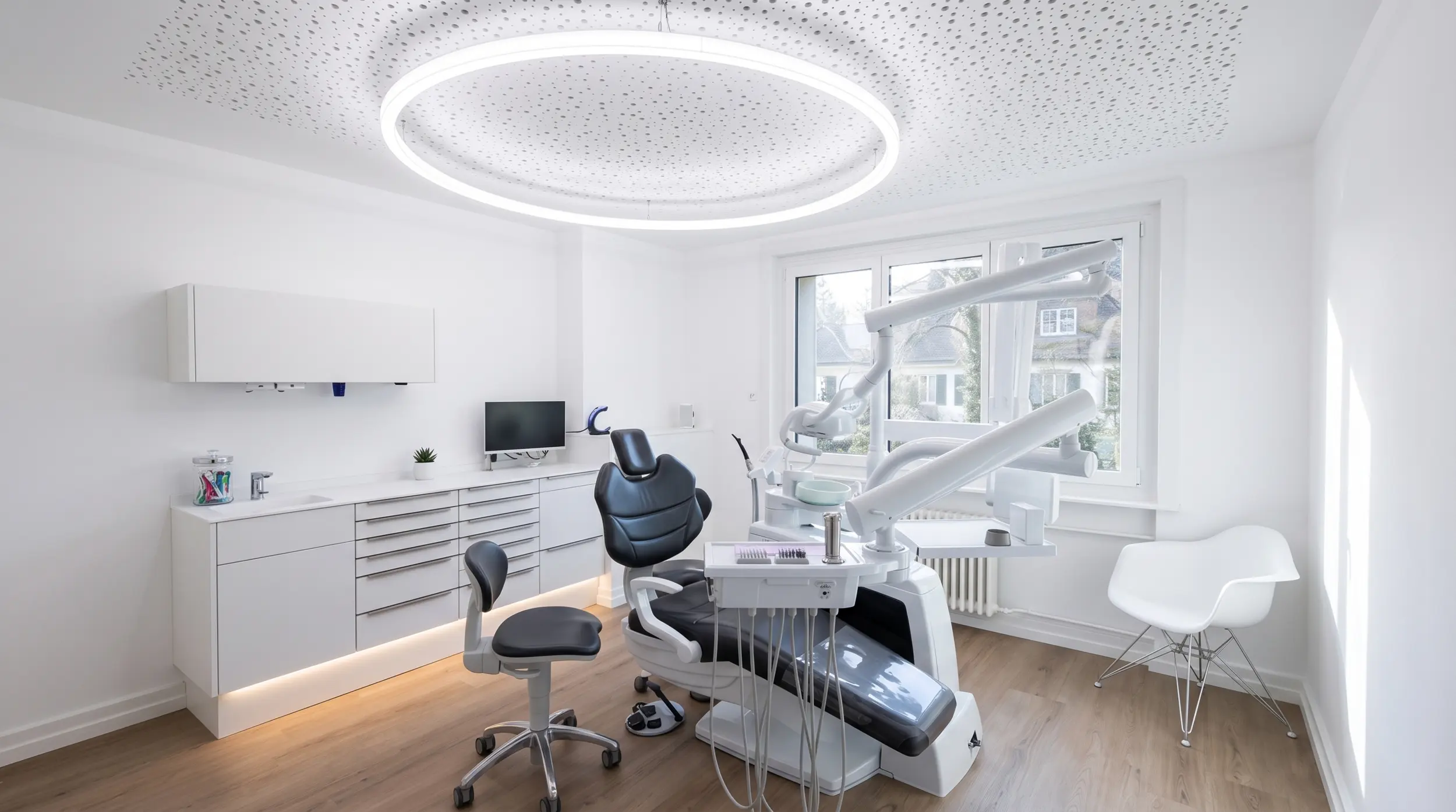 Bright treatment room of the Karamousli dental practice in Küsnacht with round ceiling light and dental chair